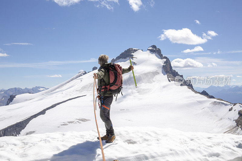 一位男性登山运动员到达了雪山的顶峰