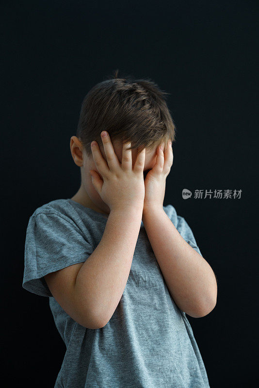 7岁的男孩非常生气，他哭了，用手捂着脸。