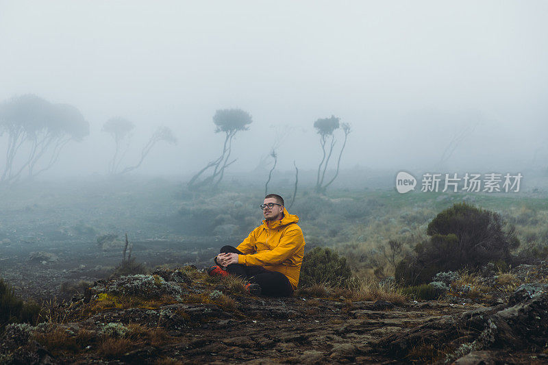 一名年轻的徒步旅行者在前往乞力马扎罗山路上风景优美的营地休息