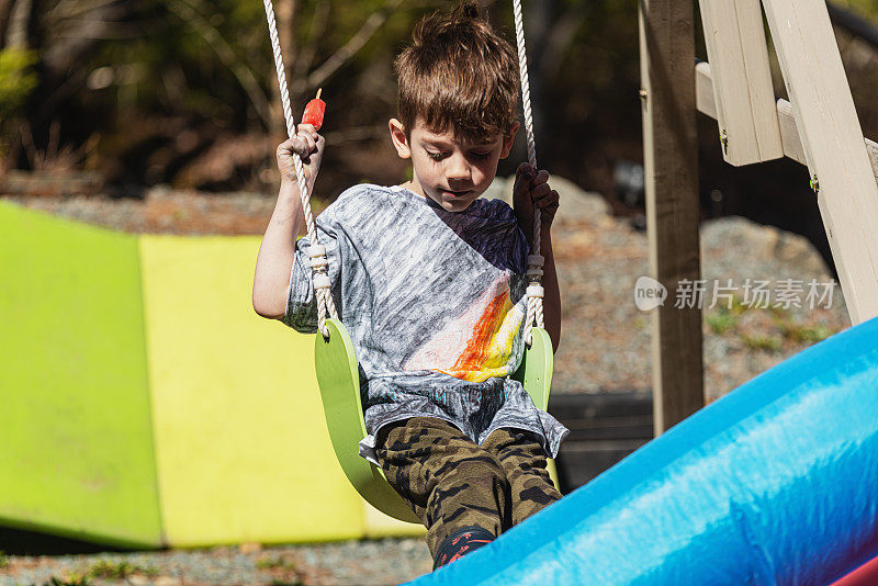 男孩喜欢在后院的操场荡秋千