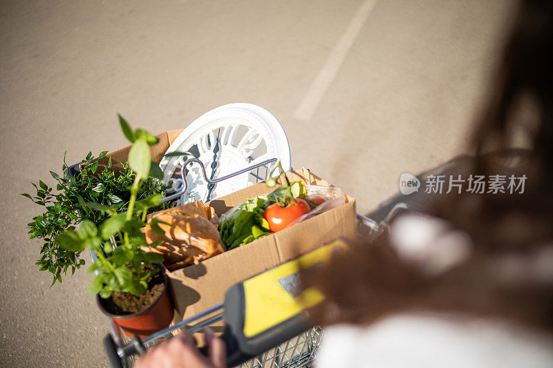 一位漂亮的年轻女子在超市买完东西，买了一些蔬菜和漂亮的花。