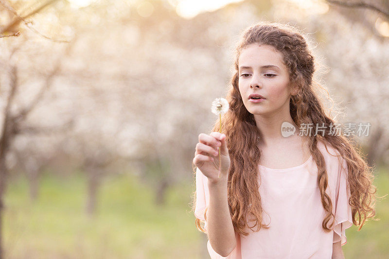 年轻美丽的女孩在春天被樱桃树包围