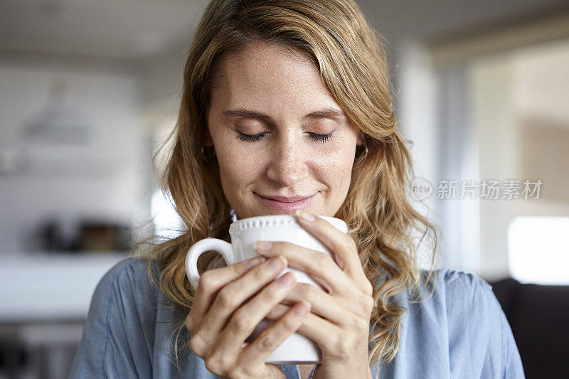 中年妇女白天在家闻着一杯咖啡的味道