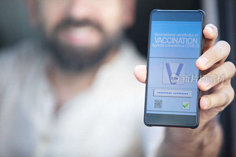 智能手机上显示的是陌生男性手中的有效疫苗接种证书
