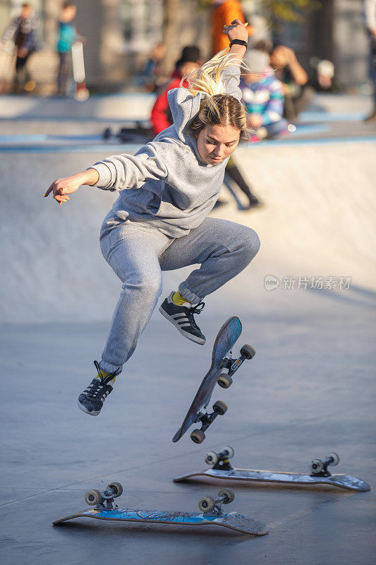 在混凝土滑板公园广场的户外滑板比赛中，年轻的滑板女孩跳过滑板