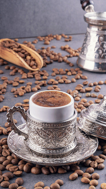土耳其咖啡和土耳其软糖与传统压花金属托盘和杯子。传统咖啡的概念。传统土耳其咖啡以黑咖啡豆为背景。
