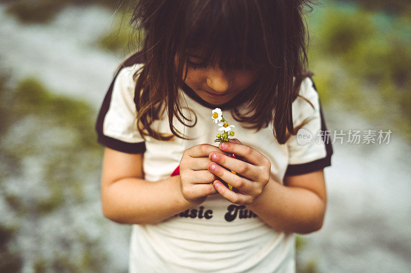 可爱的小嬉皮士女孩在复古彩虹衬衫持有一朵野花