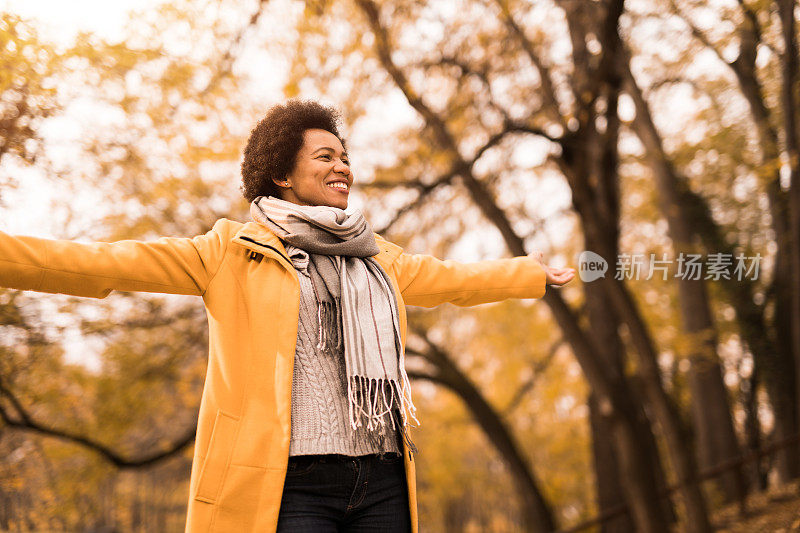 快乐的中年妇女在大自然中享受着美丽的秋日。