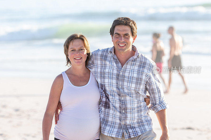 怀孕的妻子在沙滩上拥抱着她的丈夫