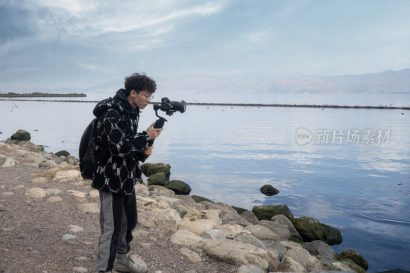 在海滩上用摄像机稳定器拍摄视频的男人