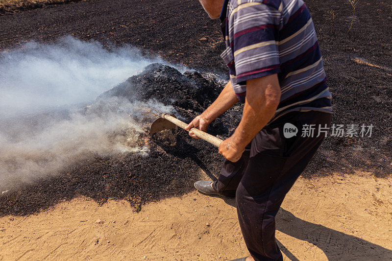 一位年长的农民在大火中奋力前行