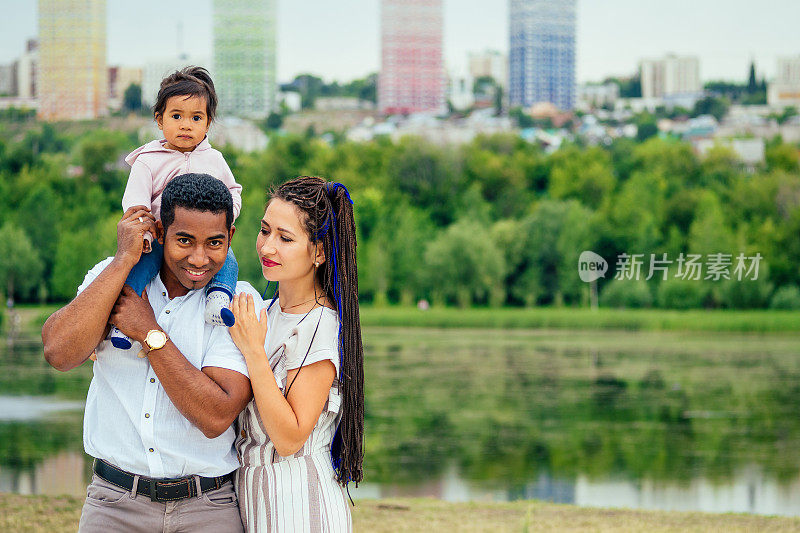 跨国跨种族的父母带着他们的混血女婴在秋天公园散步