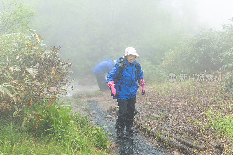 中年日本妇女走泥泞雾山路