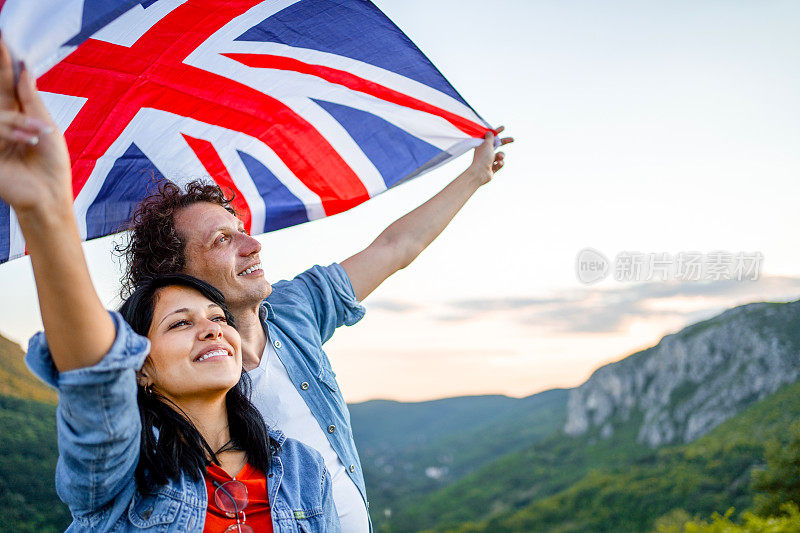 幸福的夫妇举着英国国旗站在山顶