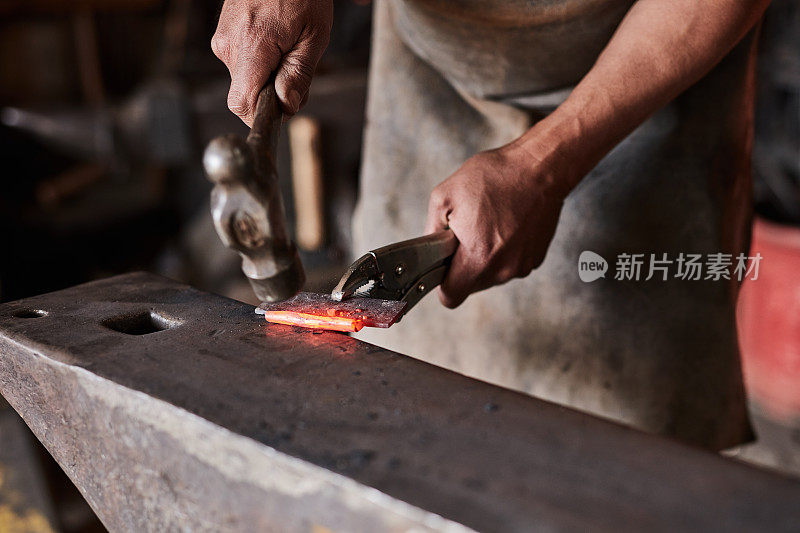 工业车间铁匠手、铁锤和铁锤在铁砧上的热锻。焊接仓库或工厂的扳手、钢铁制造工匠和金属工具的生产过程