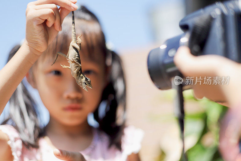 亚洲女孩和蜥蜴玩耍合影。