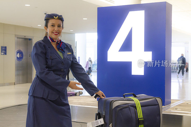 美丽的拉丁空乘人员的肖像，帮助行李在机场航站楼。欢迎所有客户或乘客乘坐飞机。旅行的概念。