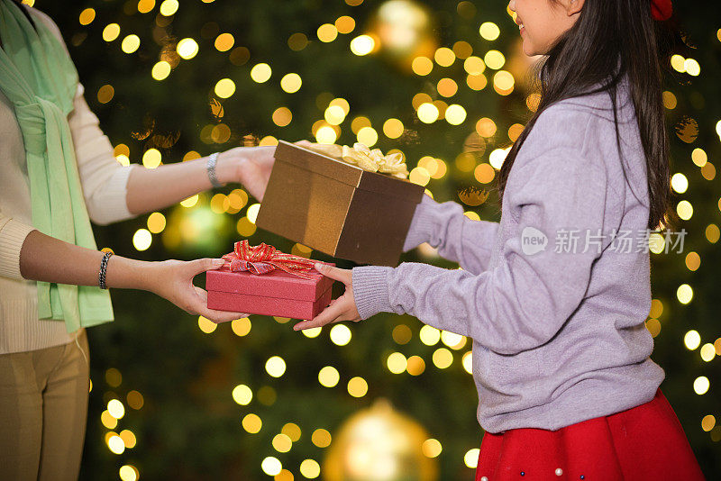 可爱的女孩与妈妈赠送和接收礼盒，交换新年礼物，圣诞节的礼盒