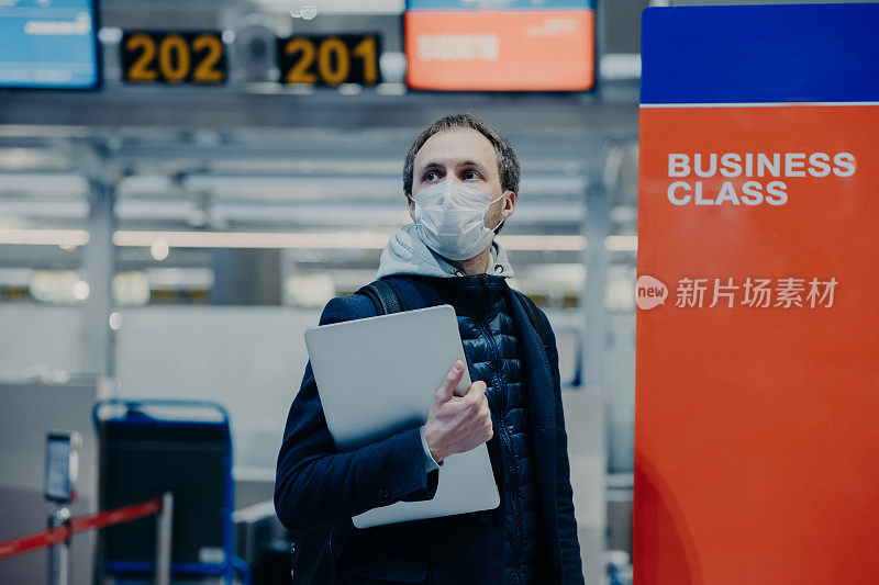 游客在机场摆姿势，希望在隔离和世界大流行期间回家，戴上防护冠状病毒的医用口罩，避免感染和病毒传播。疫情期间旅行