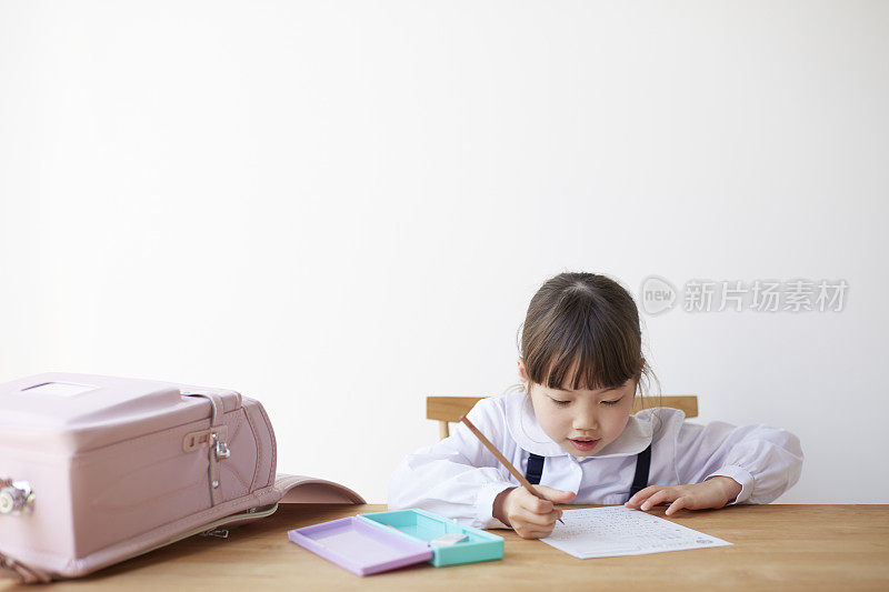 女孩学习，书包摊开在桌子上