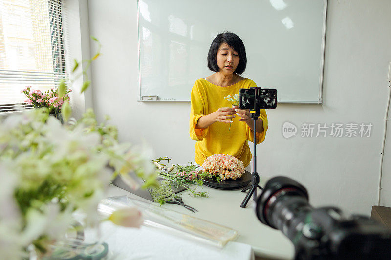 亚洲女花艺老师，小型企业花艺课程的老板，在线教授插花课程，使用智能手机，相机和笔记本电脑进行视频记录。电子学习，在线教程的概念