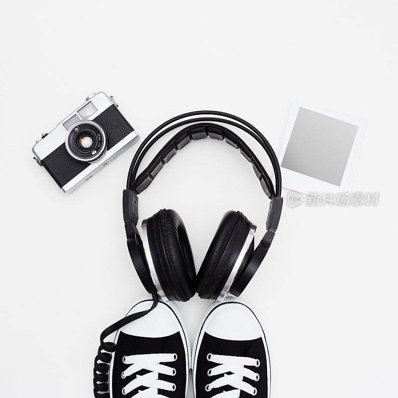 耳机，胶片相机，即时打印框架和运动鞋在白色的背景