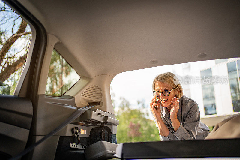 一位成熟的商务女性正在把她的衣柜和商务用品装进车里，因为她要为出差做准备。