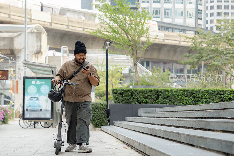 一个年轻人骑着电动滑板车沿着城市街道的小路走。