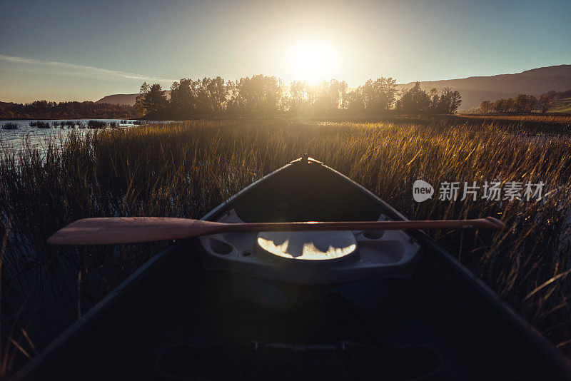 户外探险:日落时在湖中划独木舟