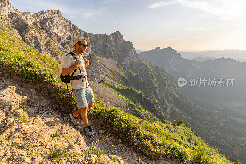 一名男子在日出时沿着长满草的山脊徒步