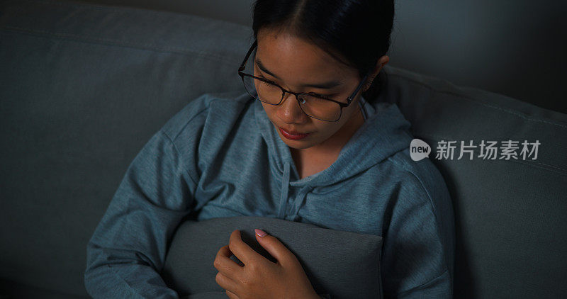 忧郁的年轻女子独自坐在沙发上思考问题