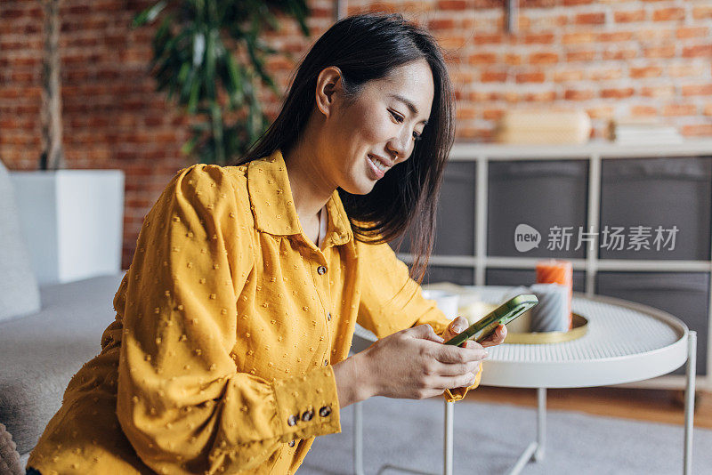 年轻的日本女子坐在地板上玩智能手机