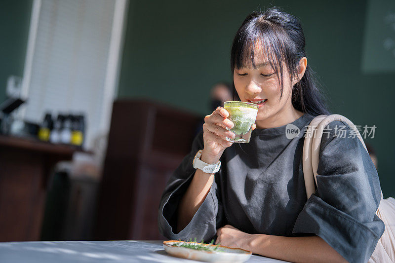 亚洲女人的热抹茶绿茶在现代咖啡馆激发了好主意。