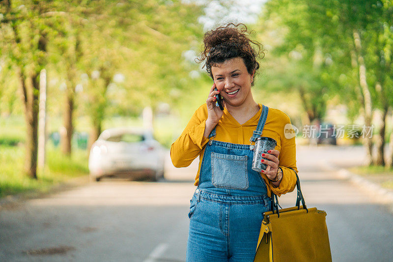 一个轻松的卷发女人一边走一边打电话。