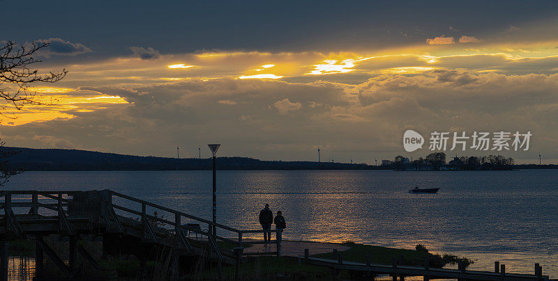 黄昏时分，一对夫妇在湖面上观看壮丽的阳光和云景