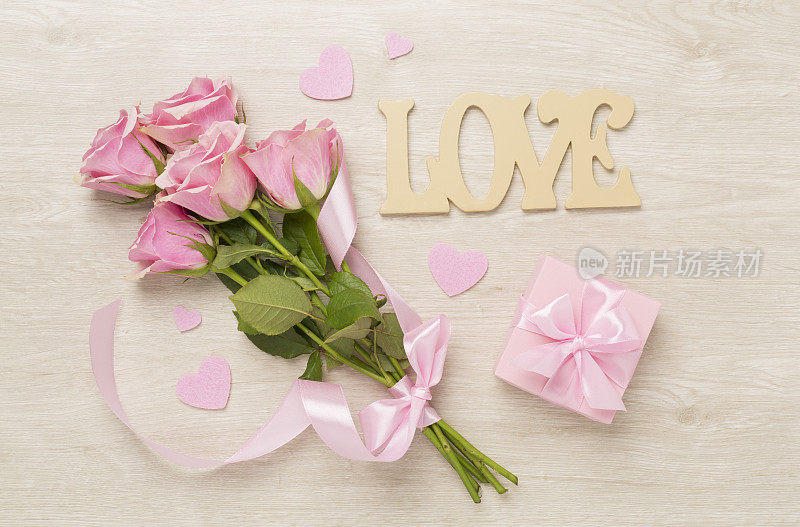粉红色玫瑰与心和礼盒木制背景，俯视图。情人节概念