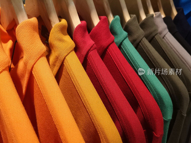 百货商店货架上挂着各种颜色的男士多色马球衫。