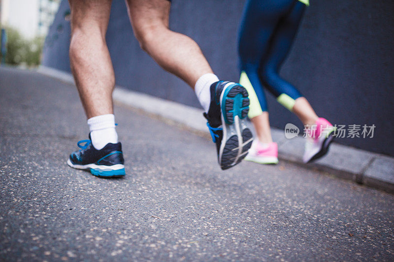一对运动员夫妇在城市的街道上晨跑。靠近腿