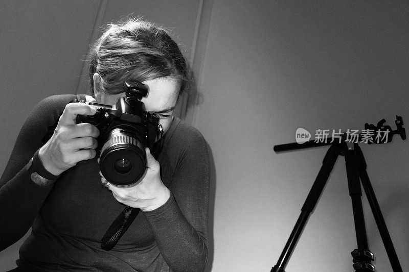 年轻女性摄影师在摄影工作室使用单反相机