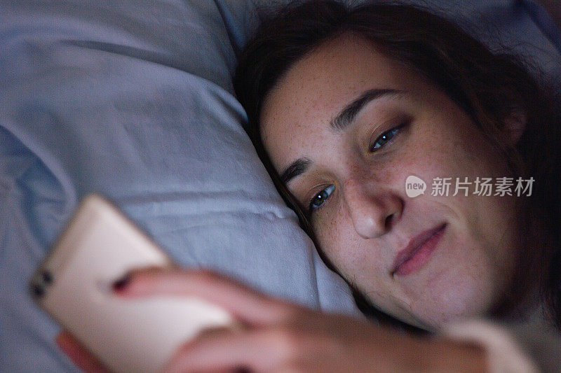 年轻女子在床上使用手机