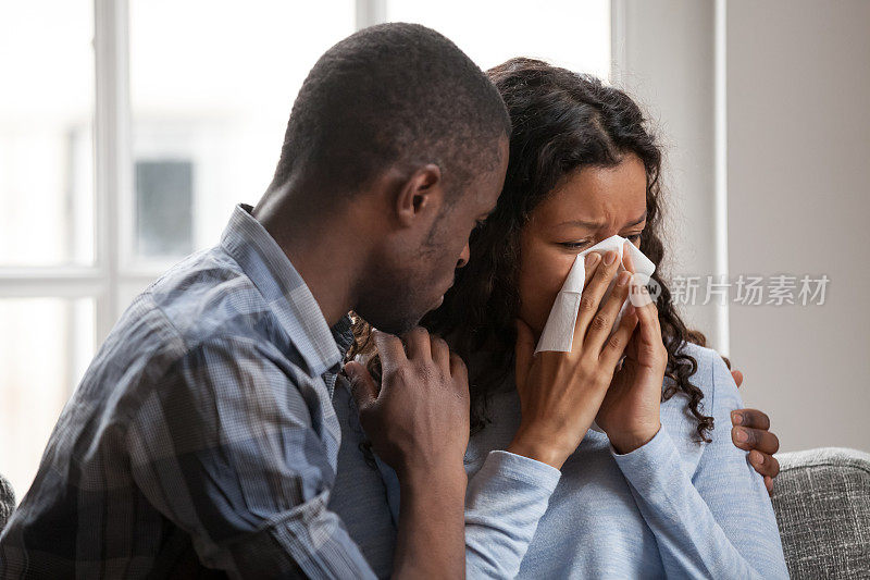 关心的黑人丈夫拥抱支持伤心哭泣的妻子