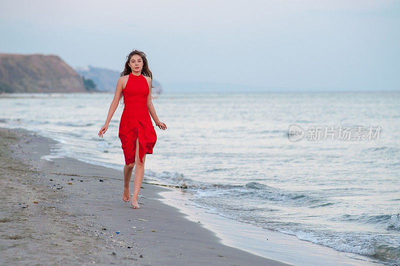 穿红衣服的年轻女子在海滩上跑步