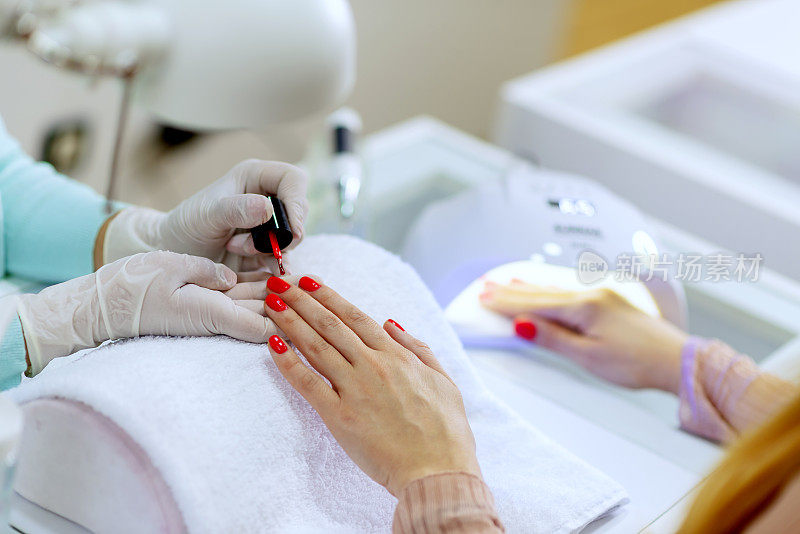 水疗中心的顾客正在用鲜红色指甲油修指甲