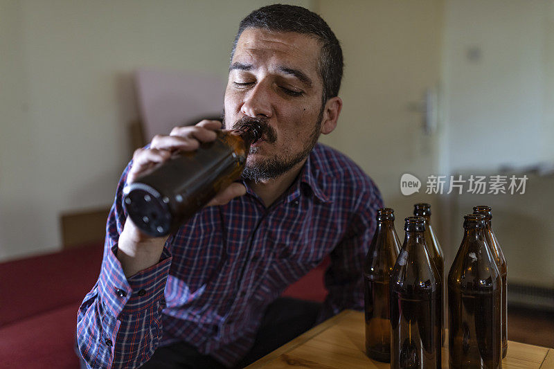 年轻悲伤的醉酒男子喝啤酒和酒精感到浪费，孤独和绝望的痛苦和情绪压力。人与酗酒、上瘾和男人抑郁的概念。