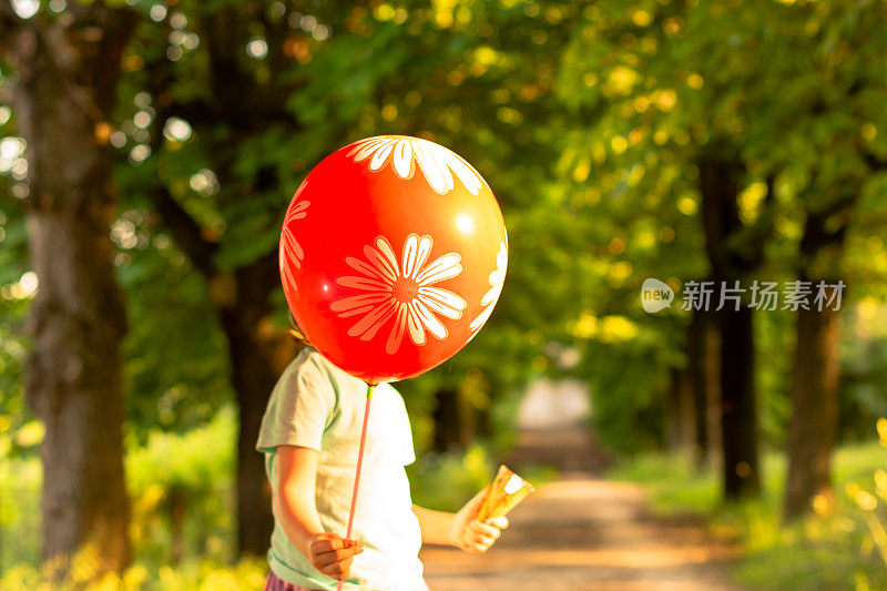 日落时分，一个女孩在公园里拿着气球。