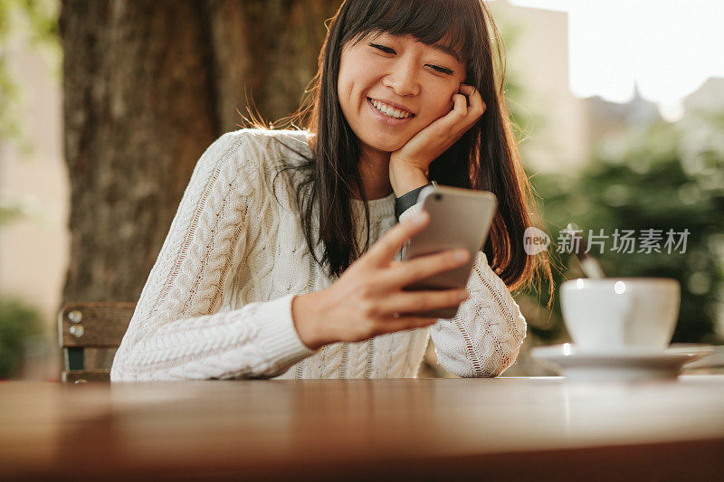 快乐的年轻女子在咖啡馆用手机