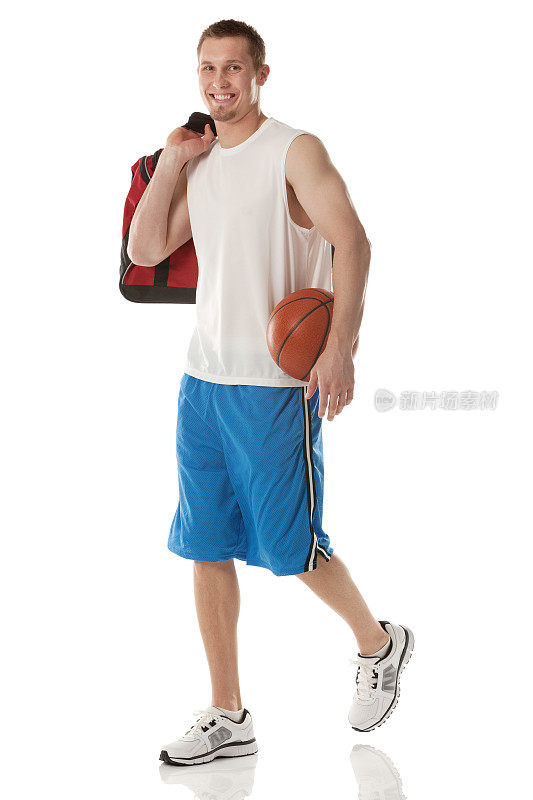 微笑的篮球运动员拿着球和包