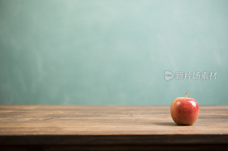 红苹果和学校黑板在木书桌上。