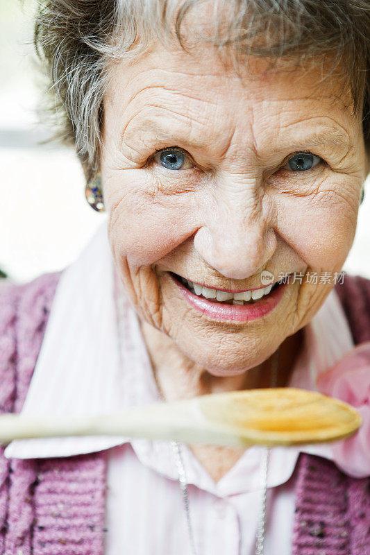 微笑的老妇人品尝木勺