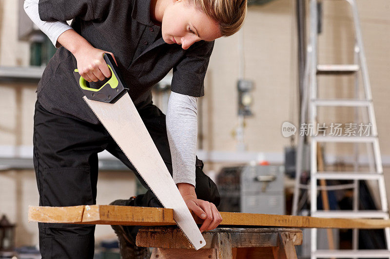 忙着用锯子切割木板的女木匠